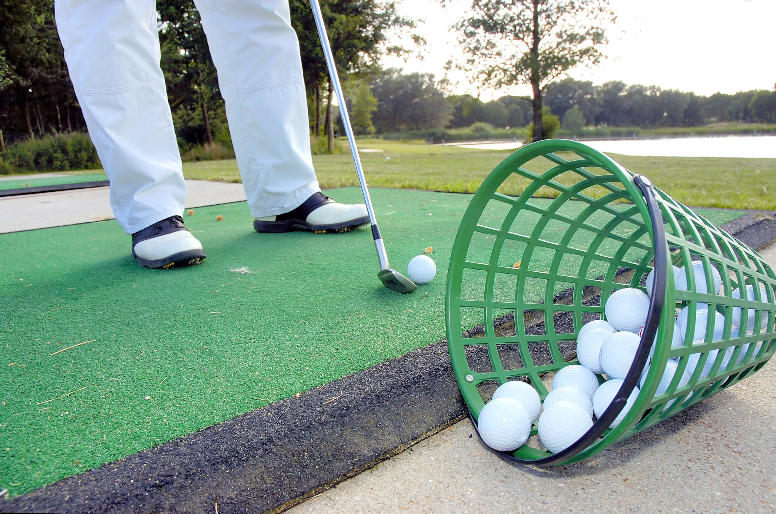 Range ball basket and golfer hitting golf balls.