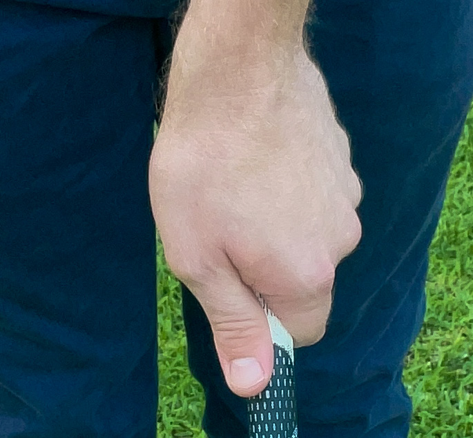 A golfer demonstrates a proper strong golf grip with the left hand. 