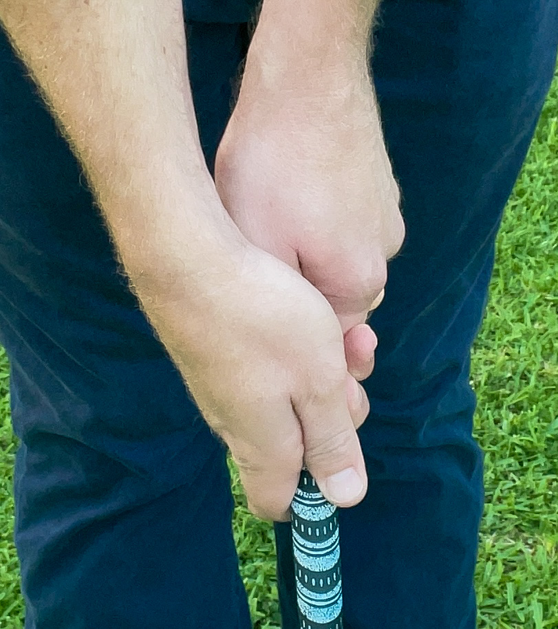 A golfer demonstrates a proper strong golf grip on a golf club. 