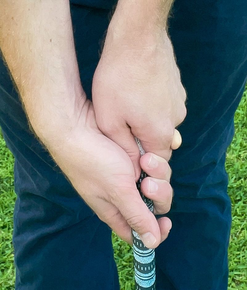 A golfer demonstrates an improper strong golf grip on a golf club. 