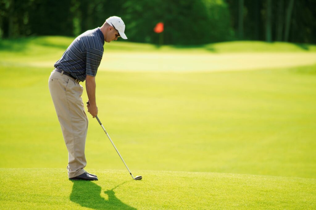 A golfer hits an approach shot to the green. 