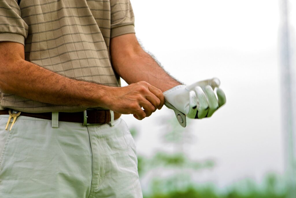 A golfer putting on a golf glove. 