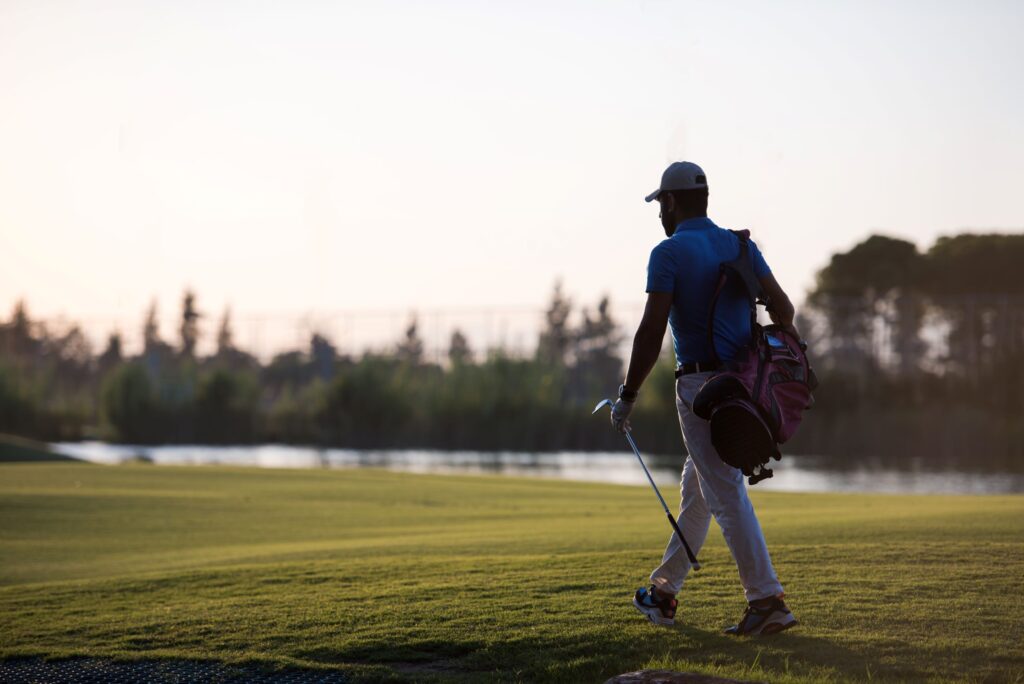 A golfer walks a golf course during a round in the early morning.