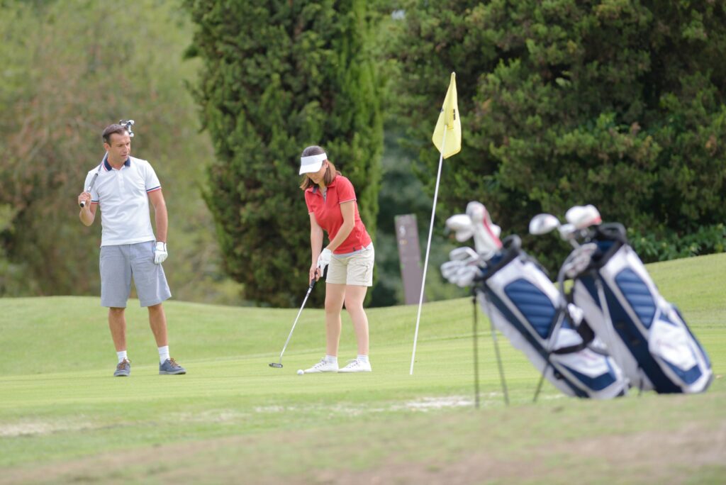 A man and woman play golf on a golf course.
