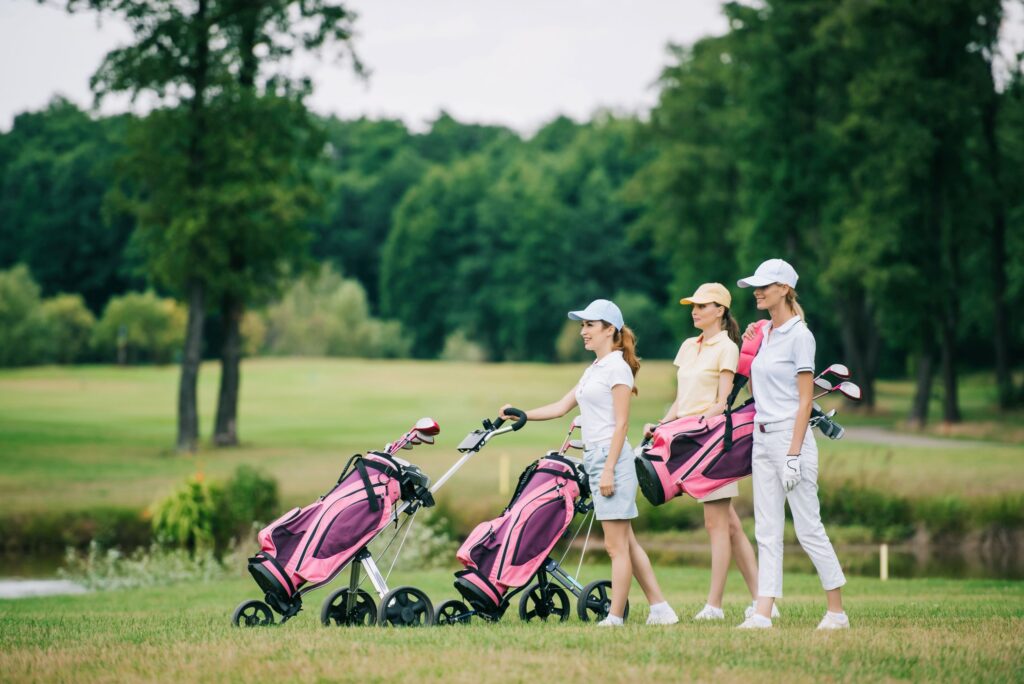 Three female golfers walking a round of golf with their golf clubs. 
