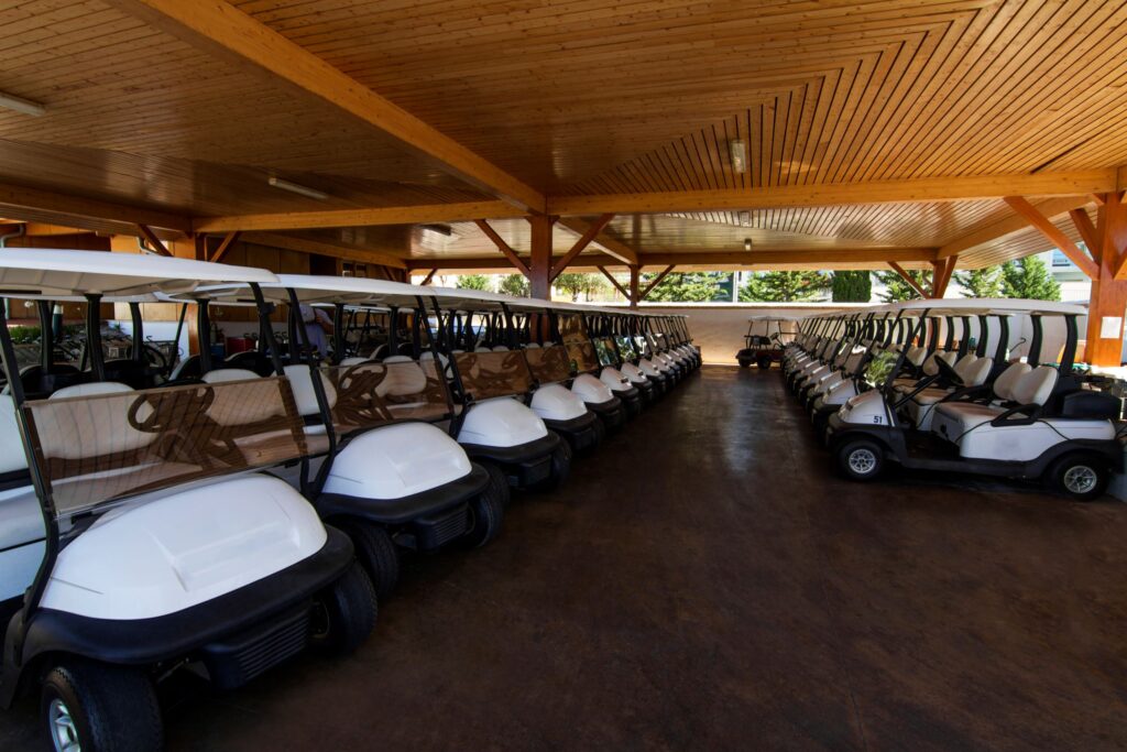 Many golf carts stored in a facility at a golf club. 