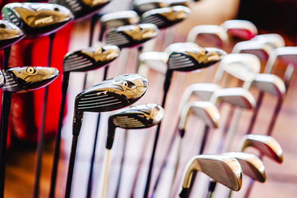 A stand in a golf equipment shop filled with various golf clubs for sale, including multiple drivers, woods, irons, and wedges. 