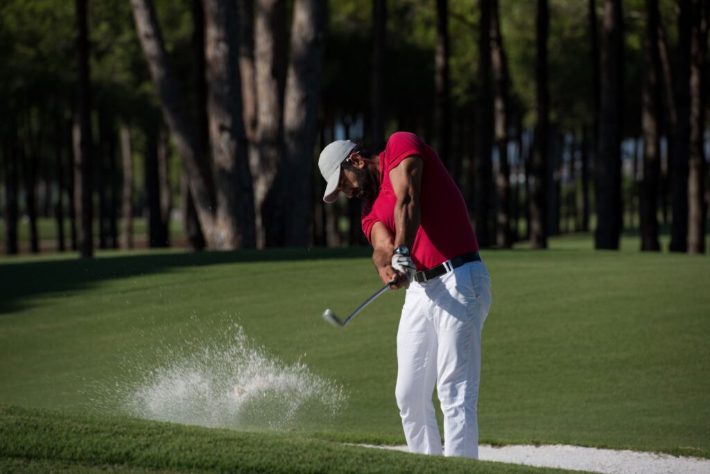 A golfer hits a bunker shot on the golf course. 