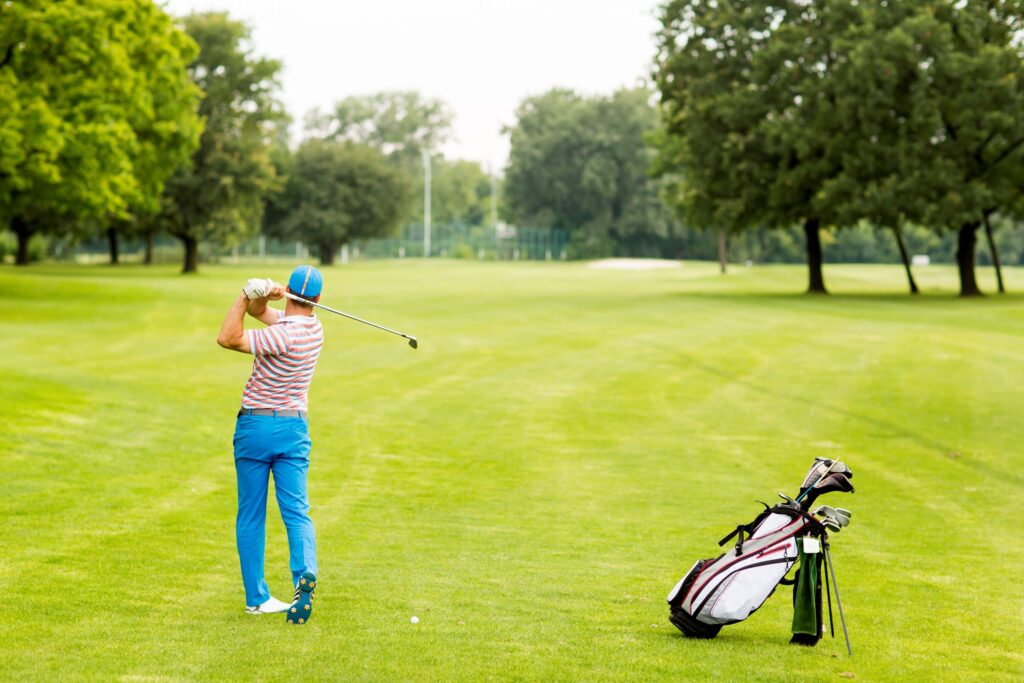 A golfer hits a shot from the fairway on a golf course. 