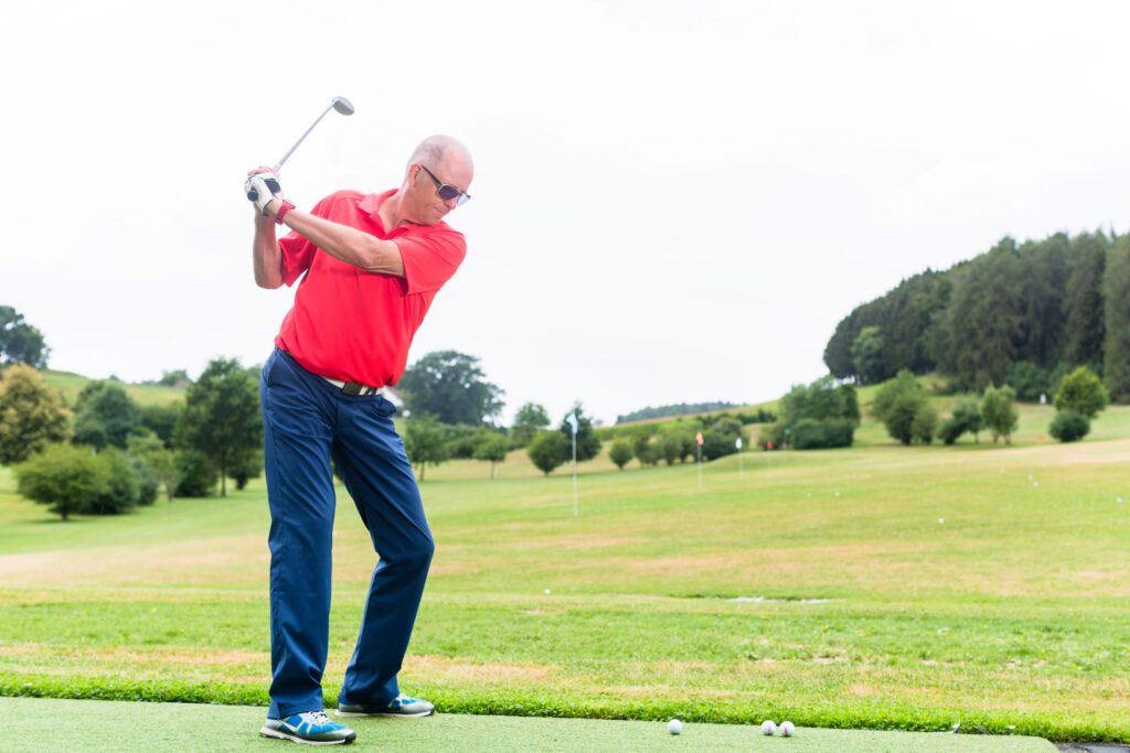 A golfer practices his golf swing on the driving range. 