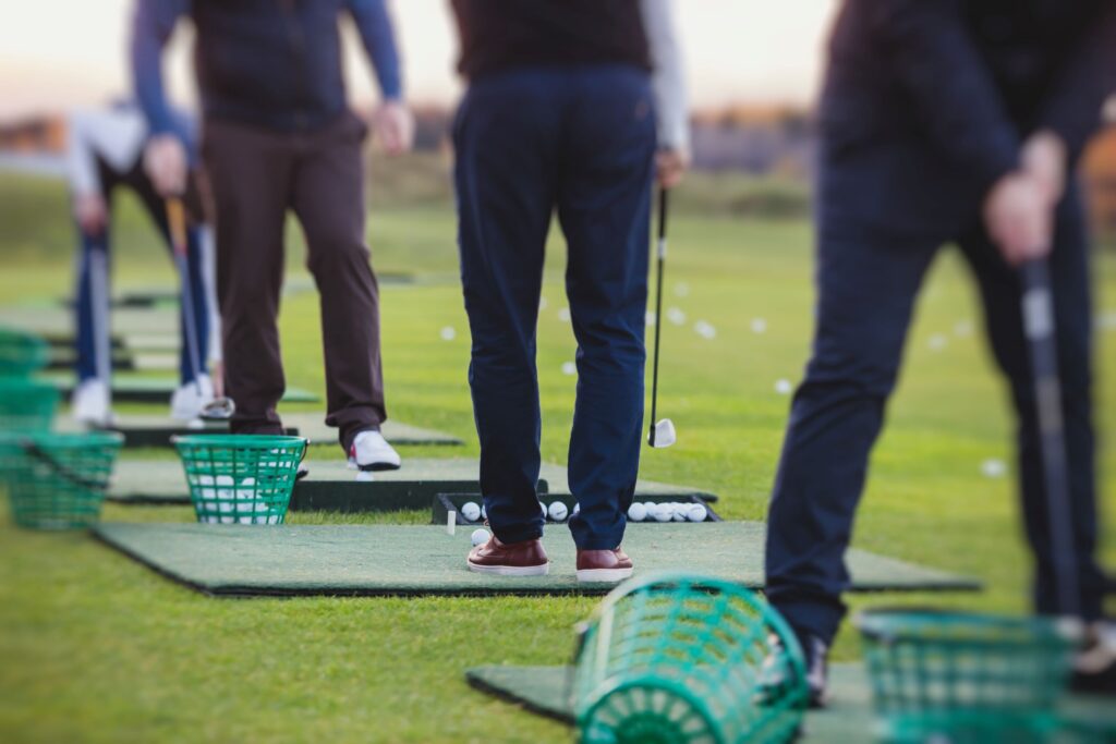 Golfers practicing their swings on the driving range. 