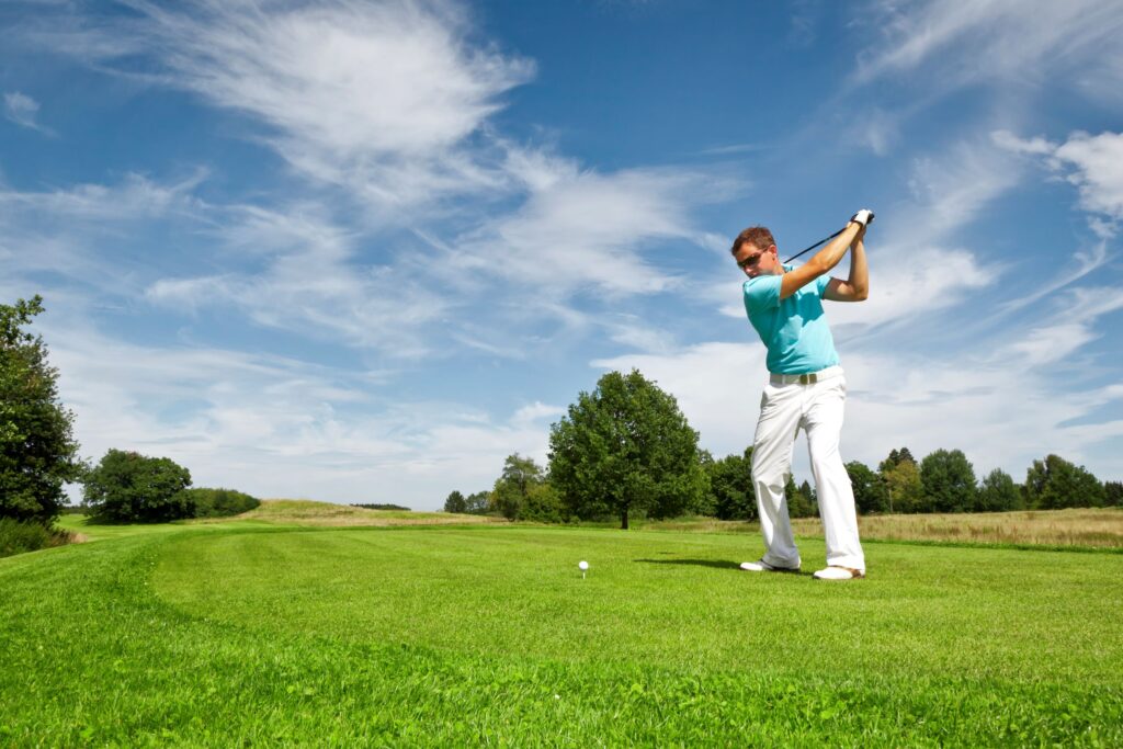 A left-handed golfer hits a drive on the golf course. 