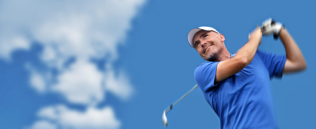A golfer smiles after hitting a golf shot. 