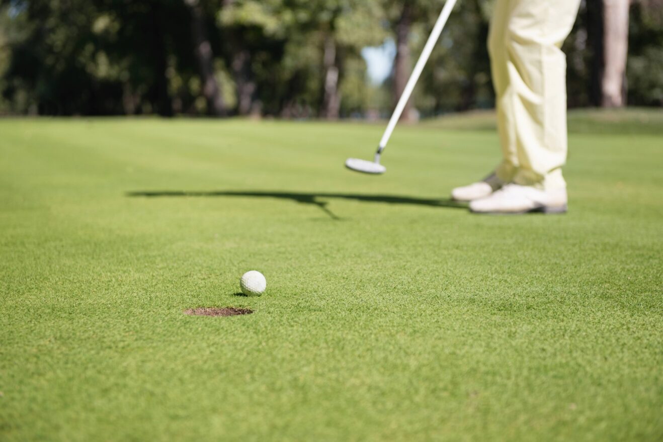 A golfer putts a ball toward a golf hole.