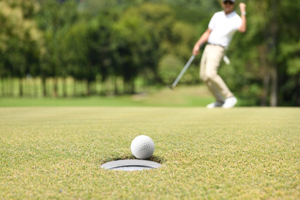 A golfer celebrates as they make a putt. 