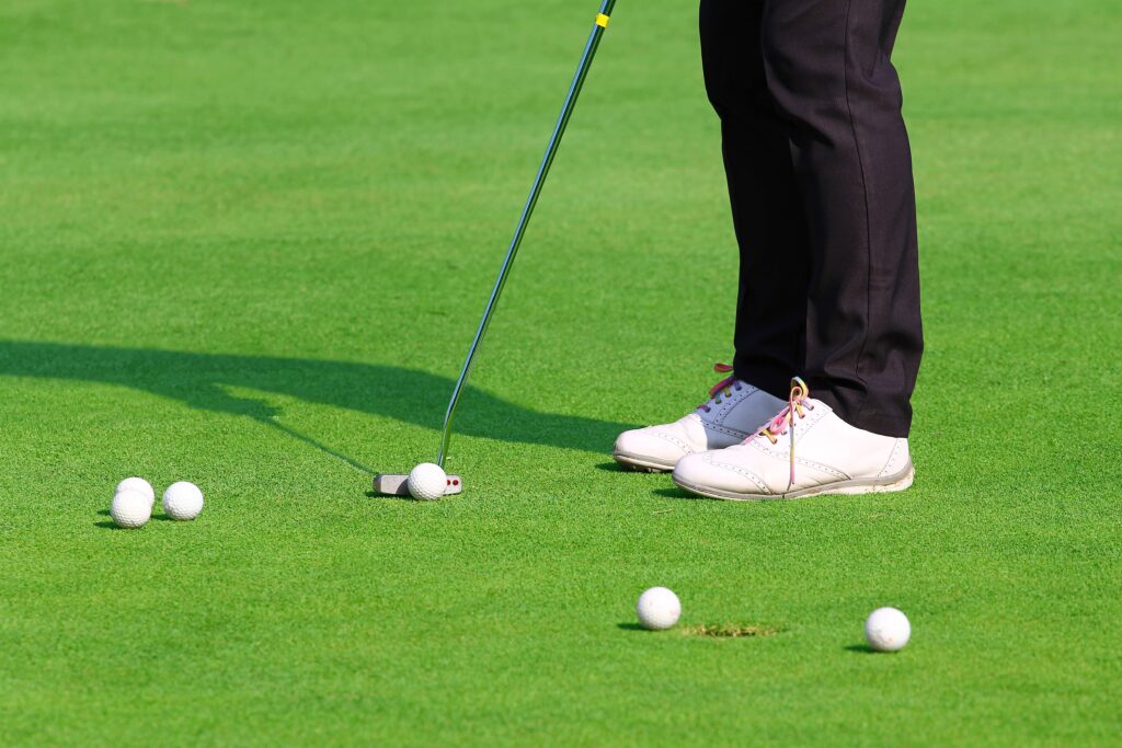 A golfer practices his putting with several golf balls. 