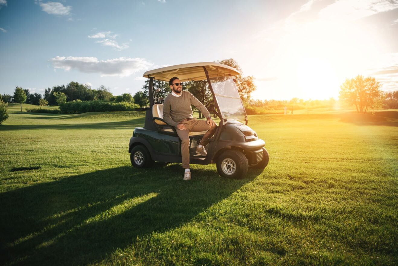 A golfer riding in a private golf cart on a golf course.