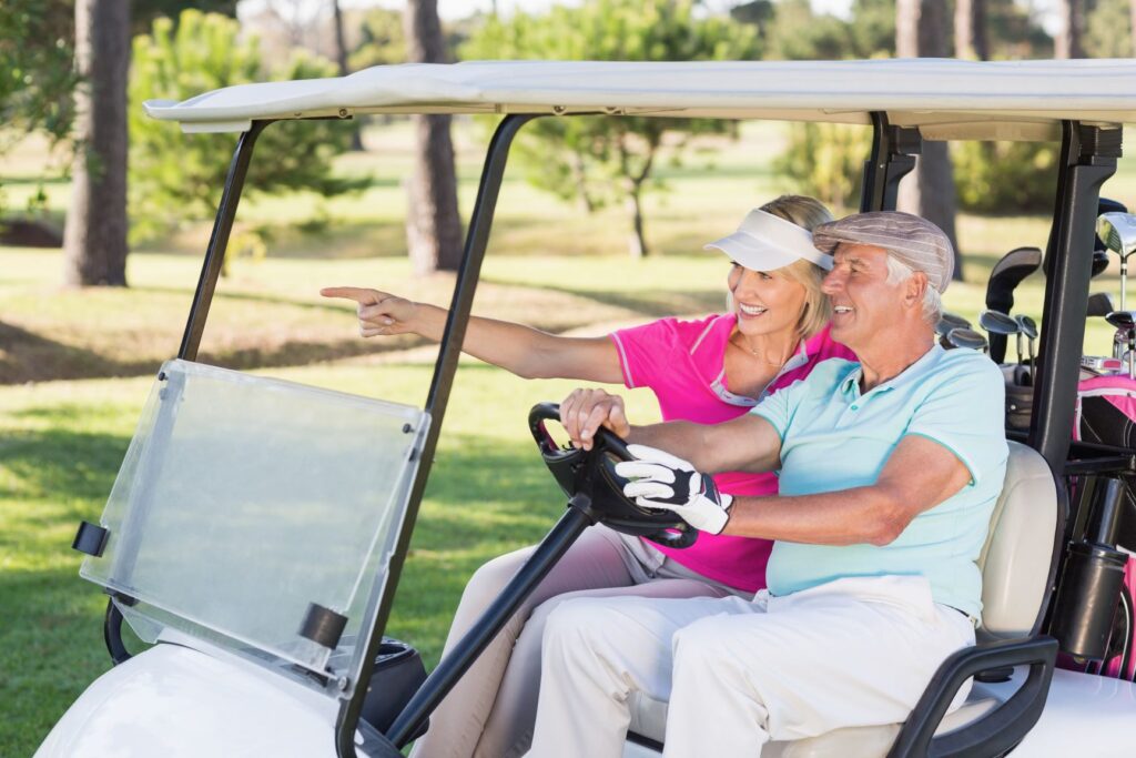 A senior couple riding in a private golf cart during a round of golf. 