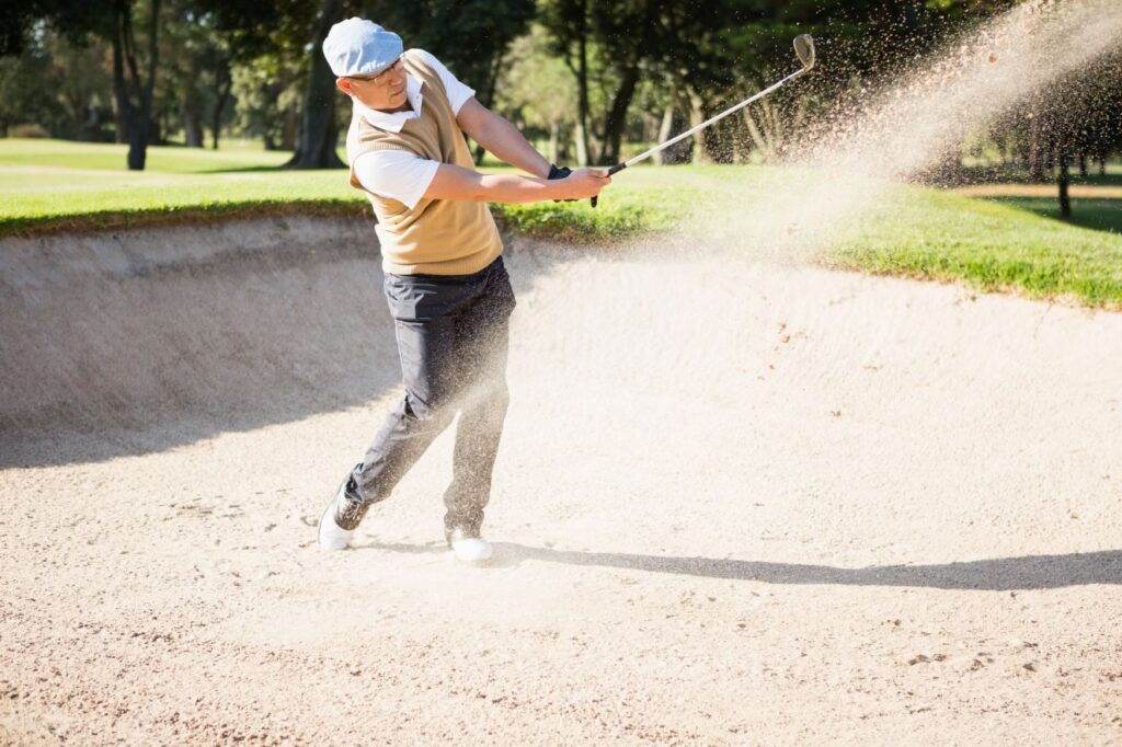 A golfer hits a bunker shot. 