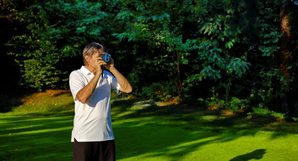 A golfer uses a rangefinder to get a distance.