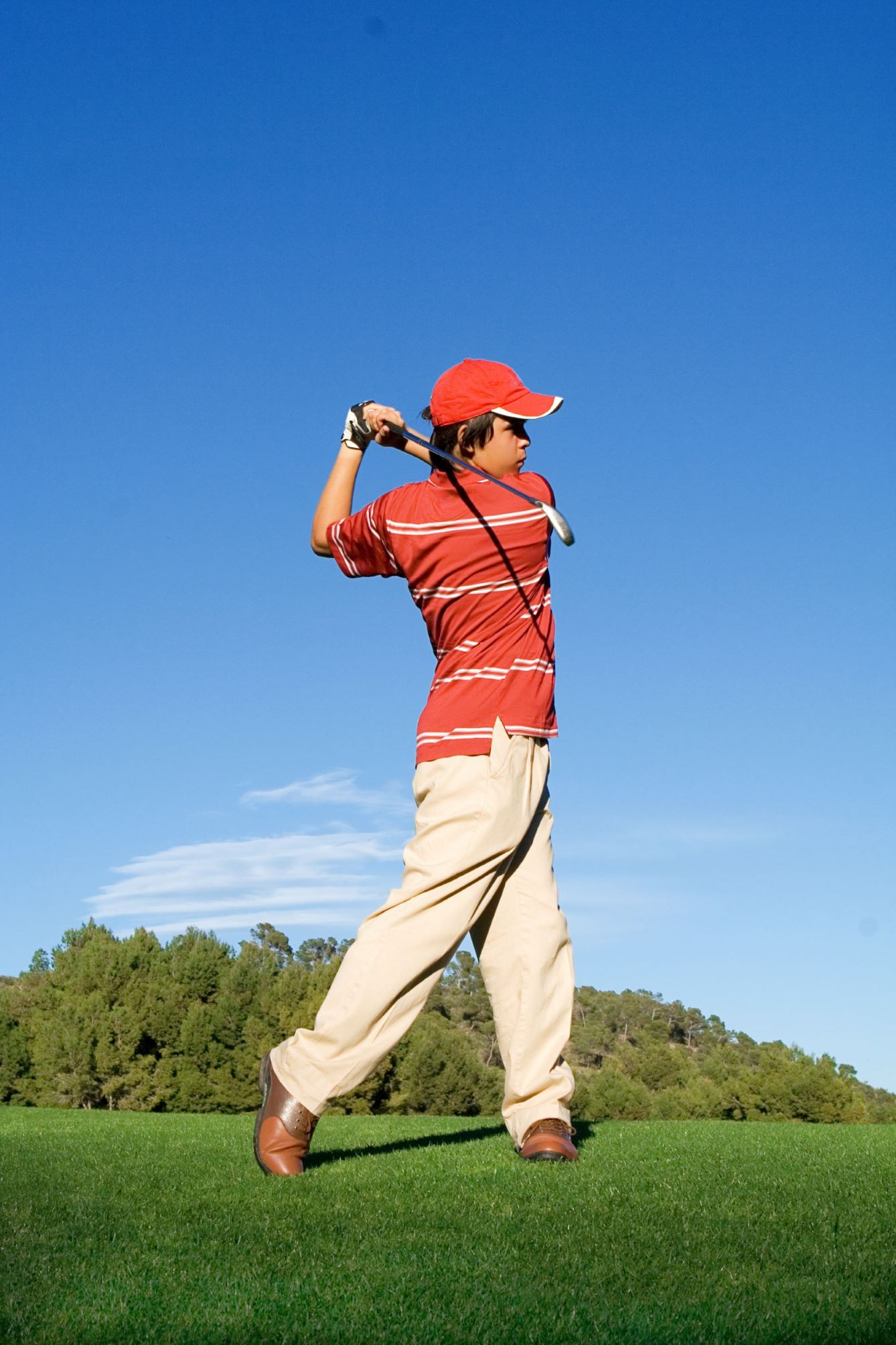 A junior golfer hitting an iron shot on the golf course.