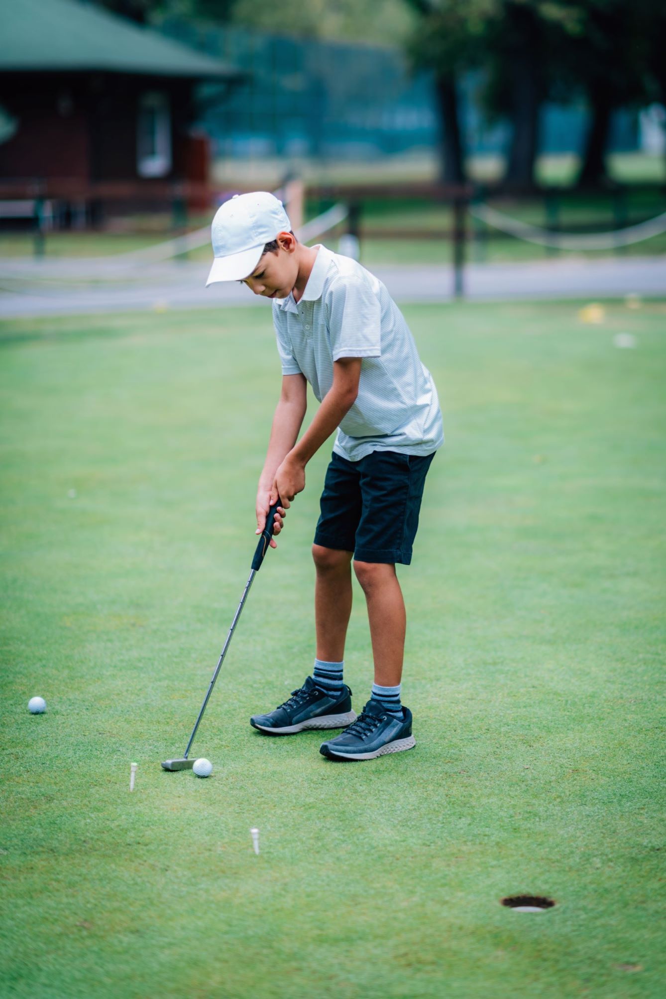 A junior golfer practicing his putting on the practice green. 
