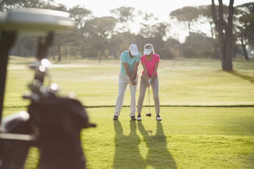 A senior golfer receives a lesson from a golf instructor. 
