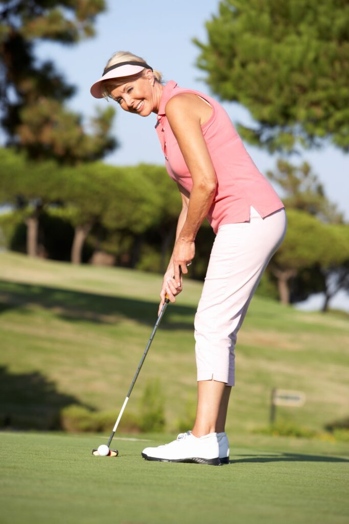 A woman golfer practicing her putting on a practice green. 