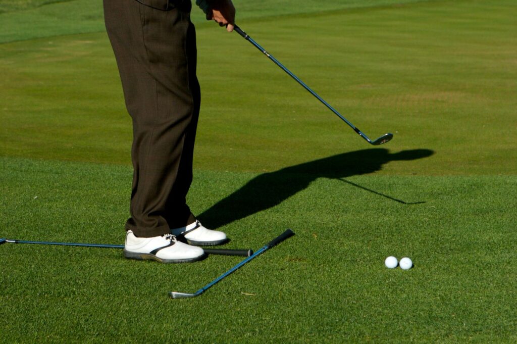A golfer practicing their alignment and ball position on a driving range. 