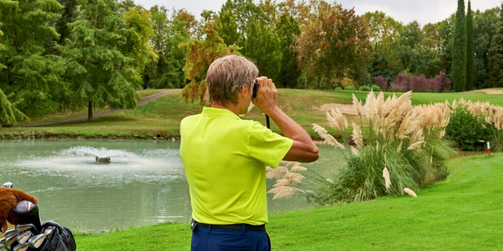 A golfer using a rangefinder to determine the distance for a golf shot on the course. 