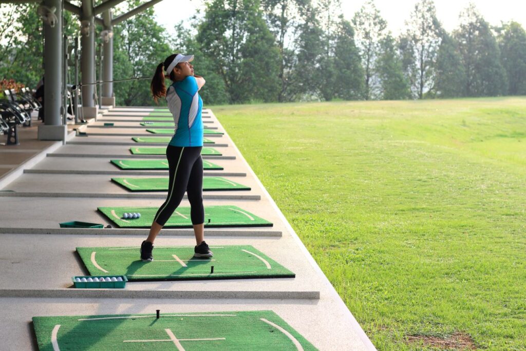 A female golfer teaching herself how to play golf on a driving range. 